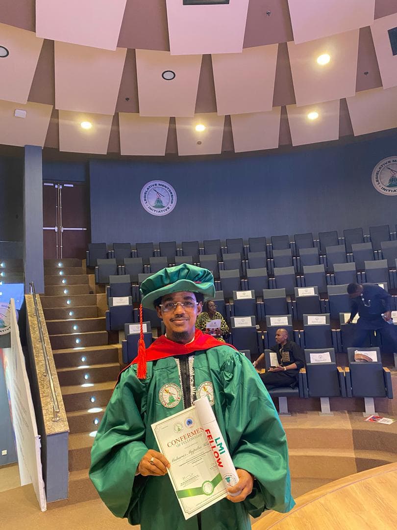 Maharaz in a green gown holding a certificate in a tiered auditorium