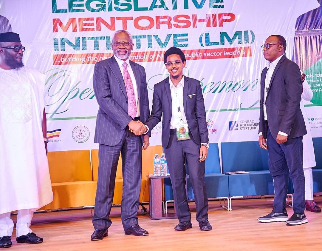 Maharaz in a dark suit shaking hands on stage at the LMI opening ceremony