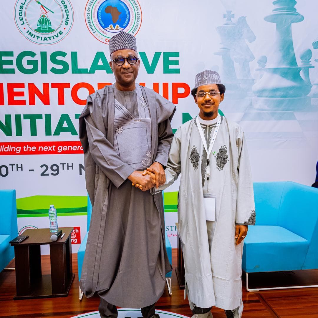 Maharaz shaking hands with a senior guest in front of a Legislative Mentorship Initiative backdrop