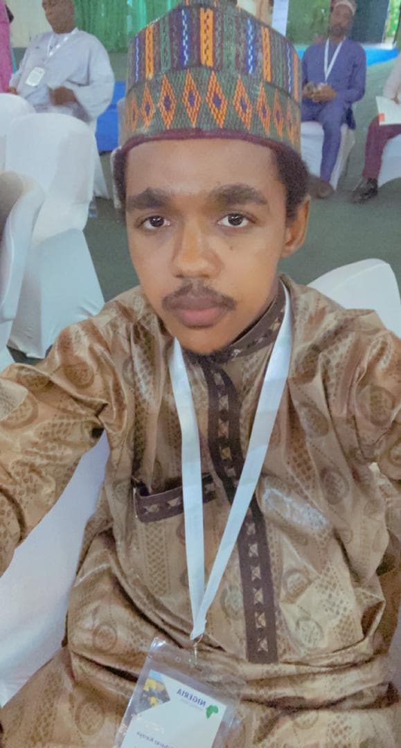 Maharaz in a patterned cap and gold kaftan wearing a delegate badge