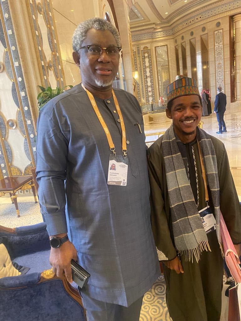 Maharaz with an older delegate wearing a conference lanyard in an ornate hall