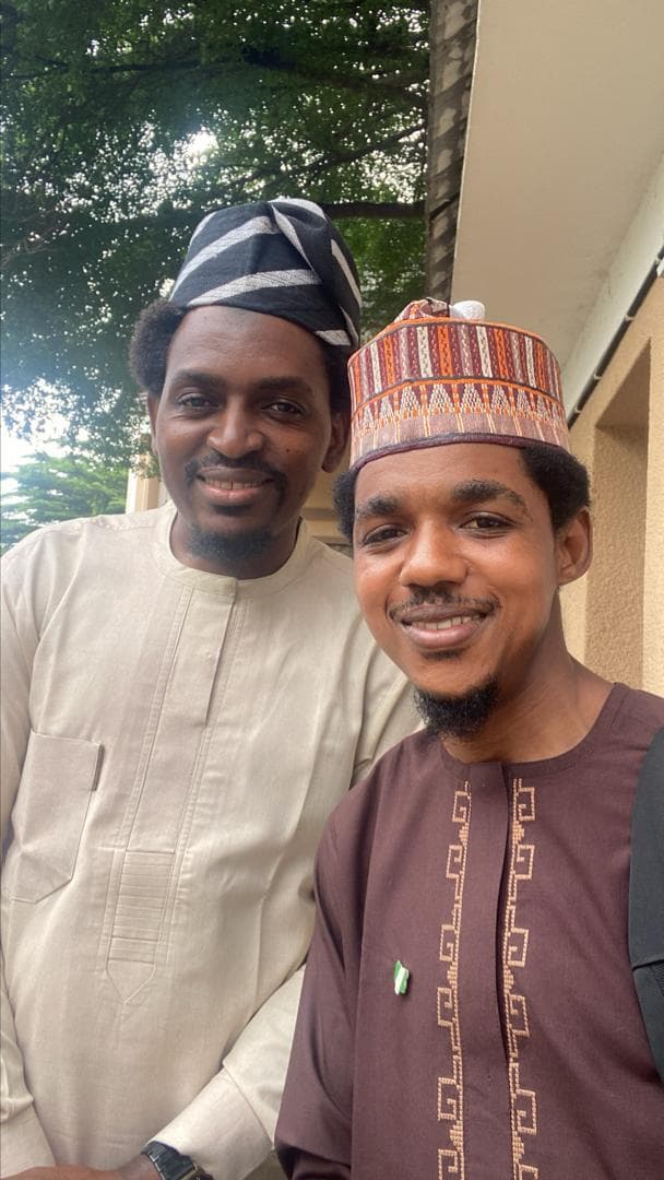 Maharaz smiling alongside a friend, both in traditional caps