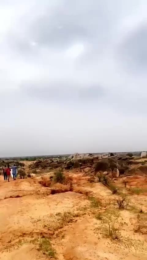 Video still of open rocky terrain with laterite soil under a cloudy sky