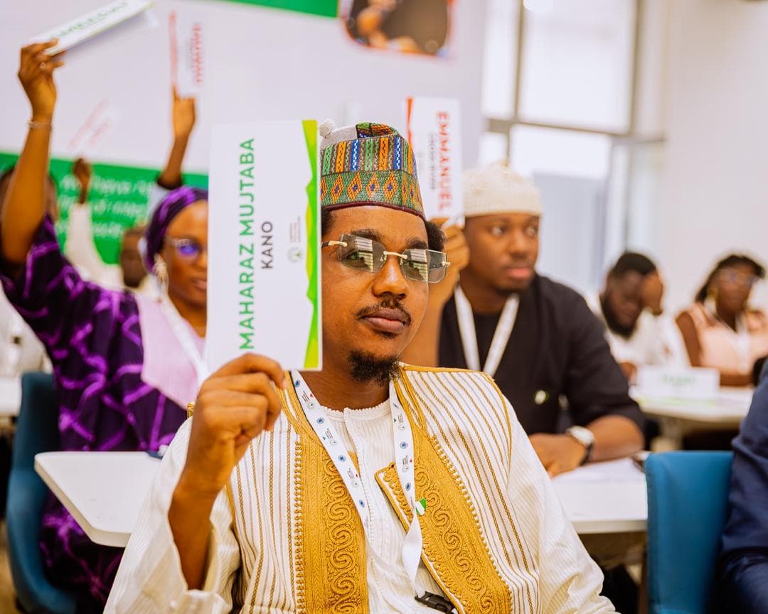 Maharaz holding up a name card reading 'Maharaz Mujtaba, Kano' during a session